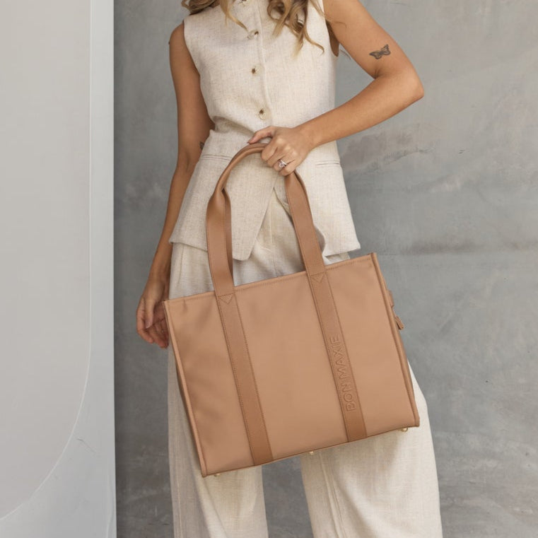 Woman holding a beige tote bag in a minimalistic indoor setting