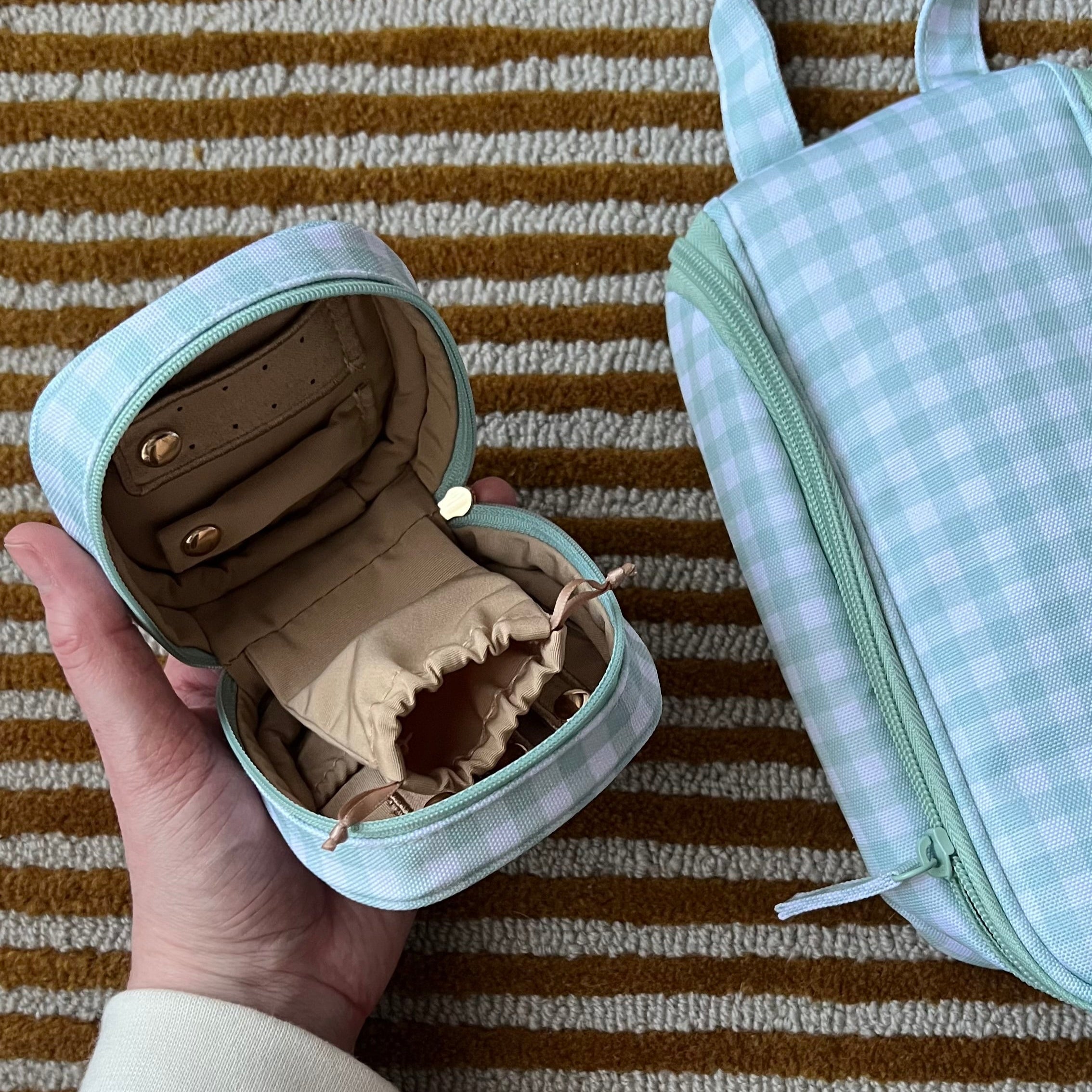 Small jewelry box with a ring inside, held by a hand on a striped fabric background
