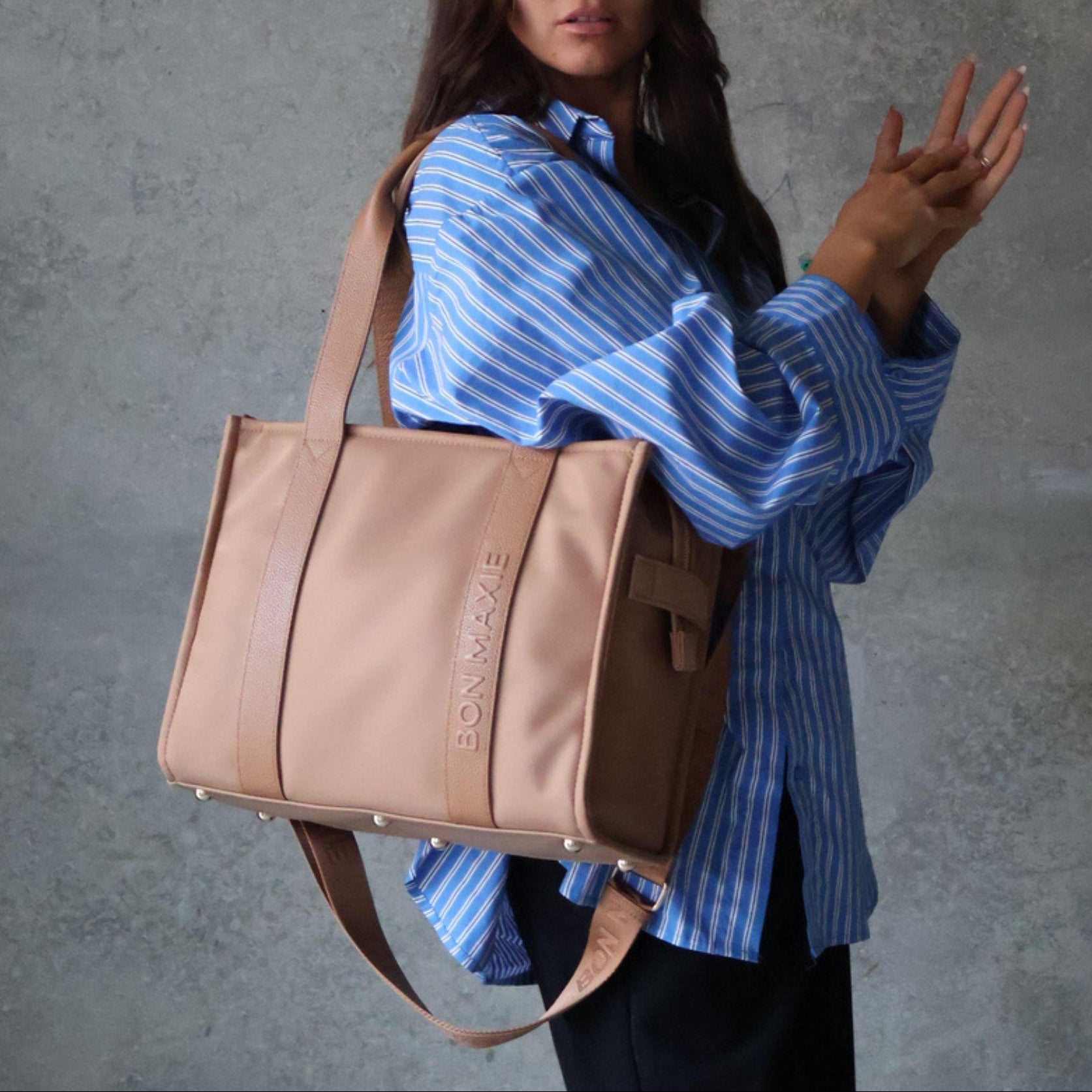 Load video: Woman demonstrating medium nylon leather tote in tan