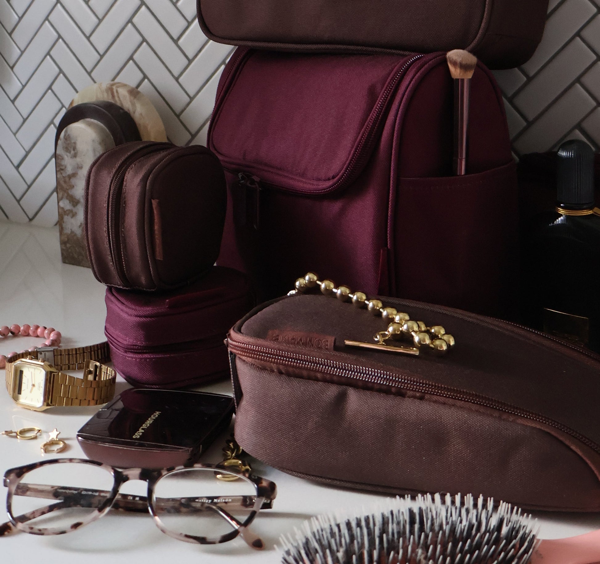 Maroon bags with gold chains on a white tiled floor.