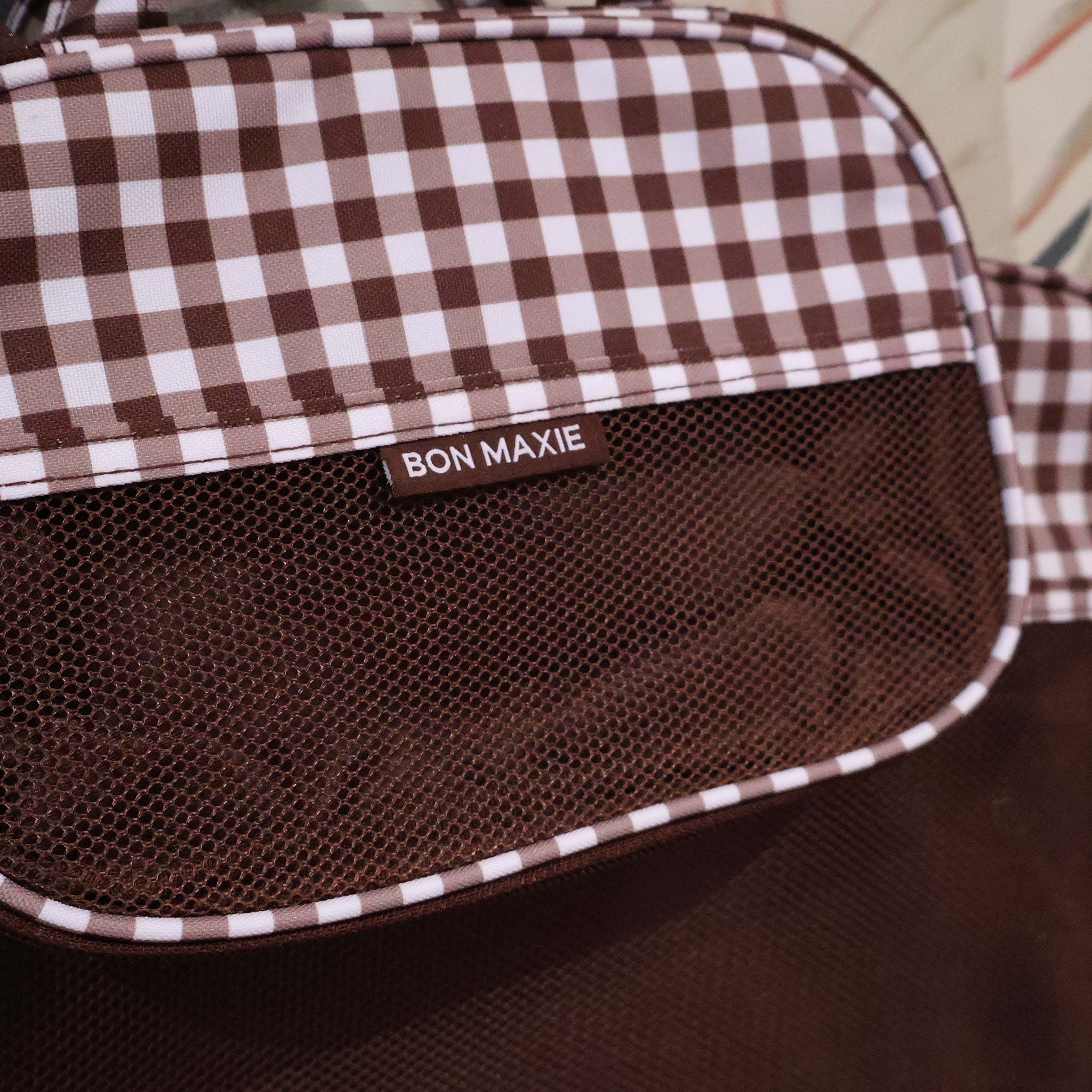 Brown and white checkered bag with 'Bon Maxie' branding on a blurred background