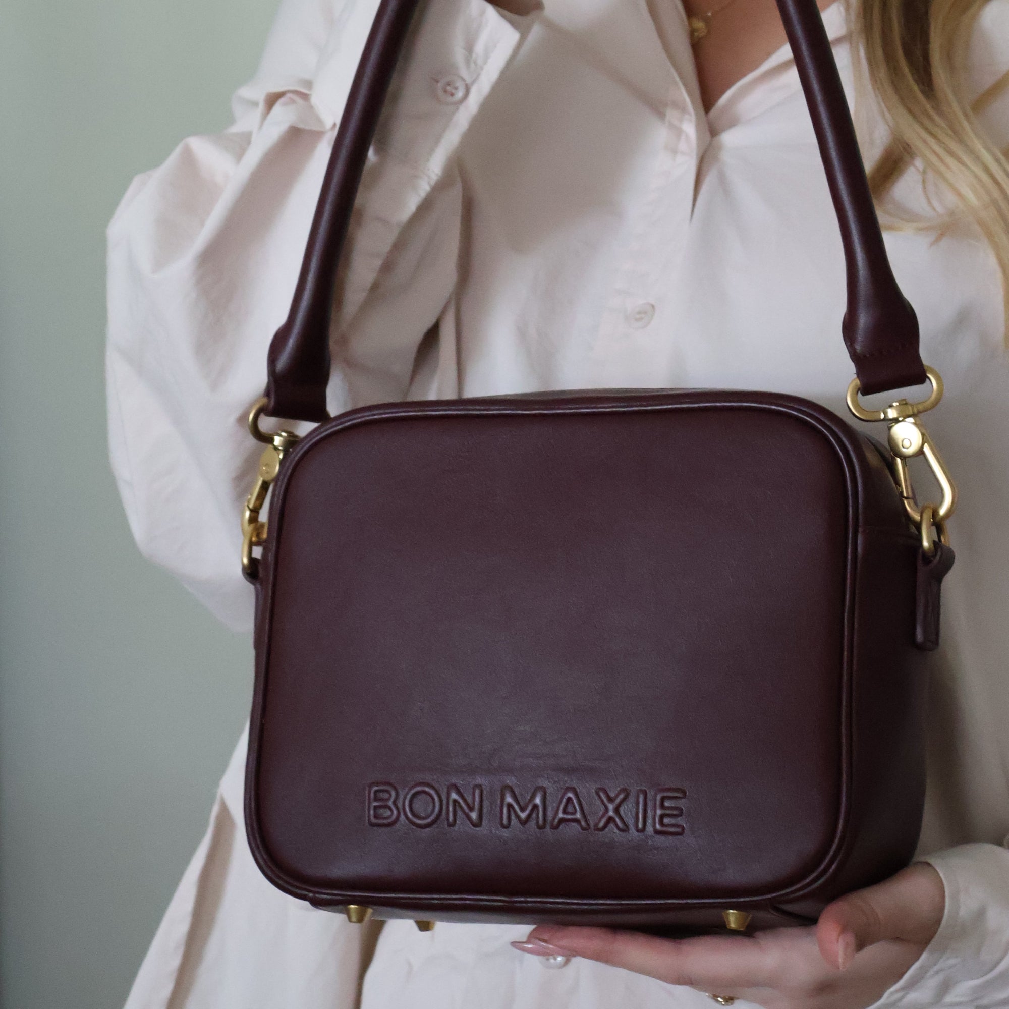 Person holding a burgundy shoulder leather handbag.