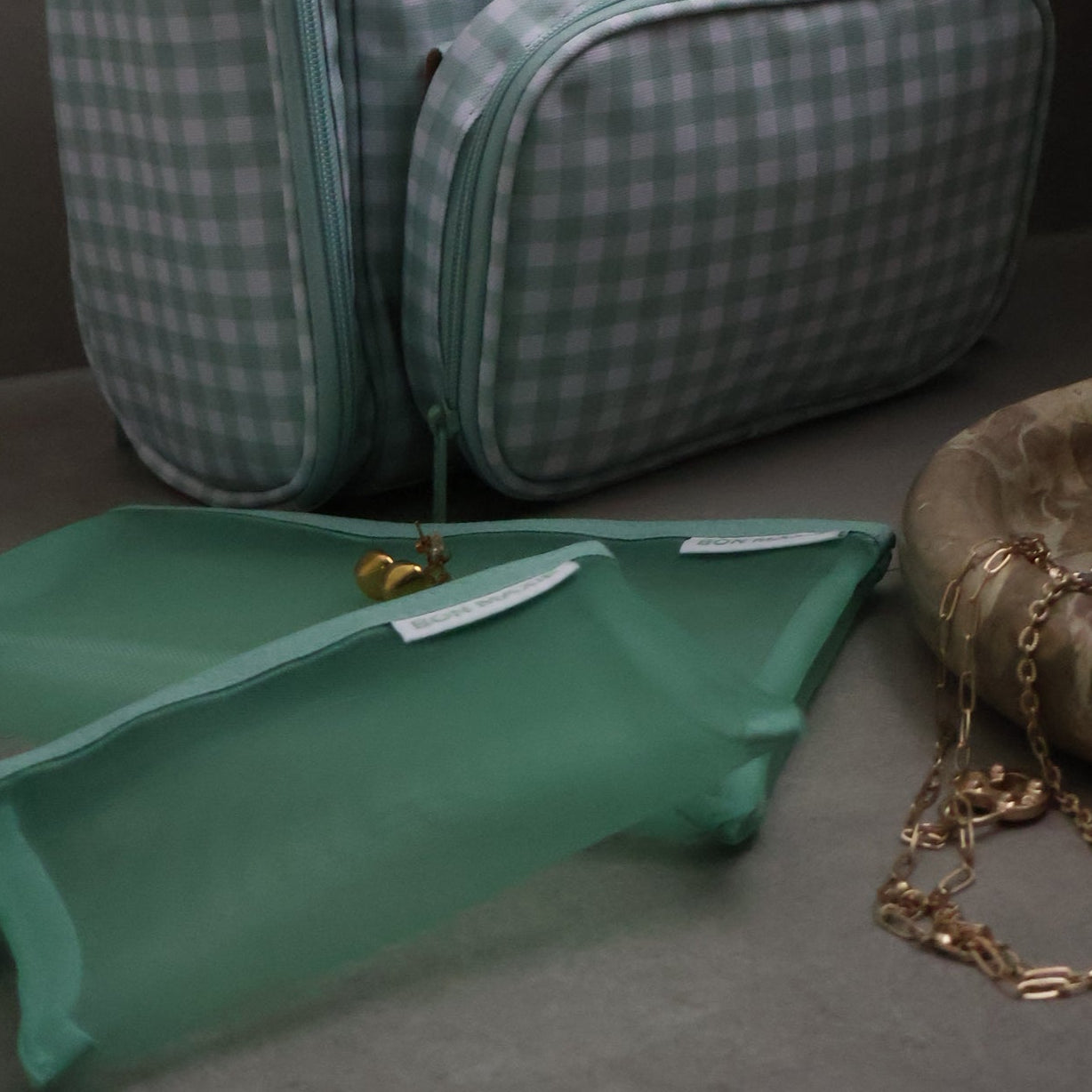 Green checkered toiletry bag on a gray surface with a neutral background