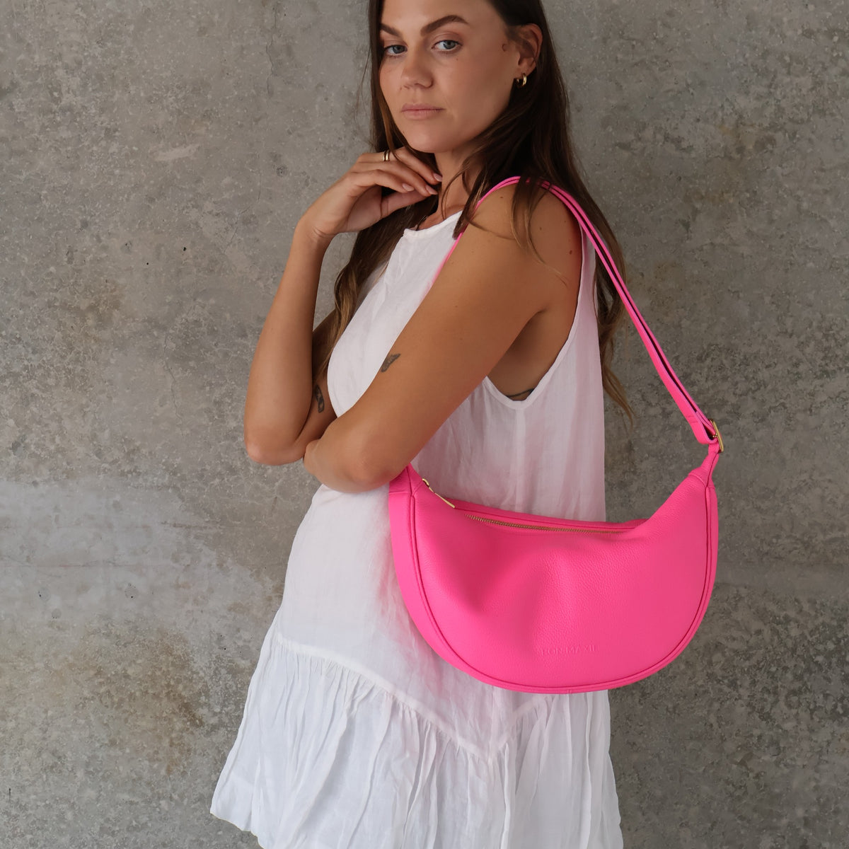 Slouchy Crescent Crossbody Bag in Neon Pink, worn on the shoulder