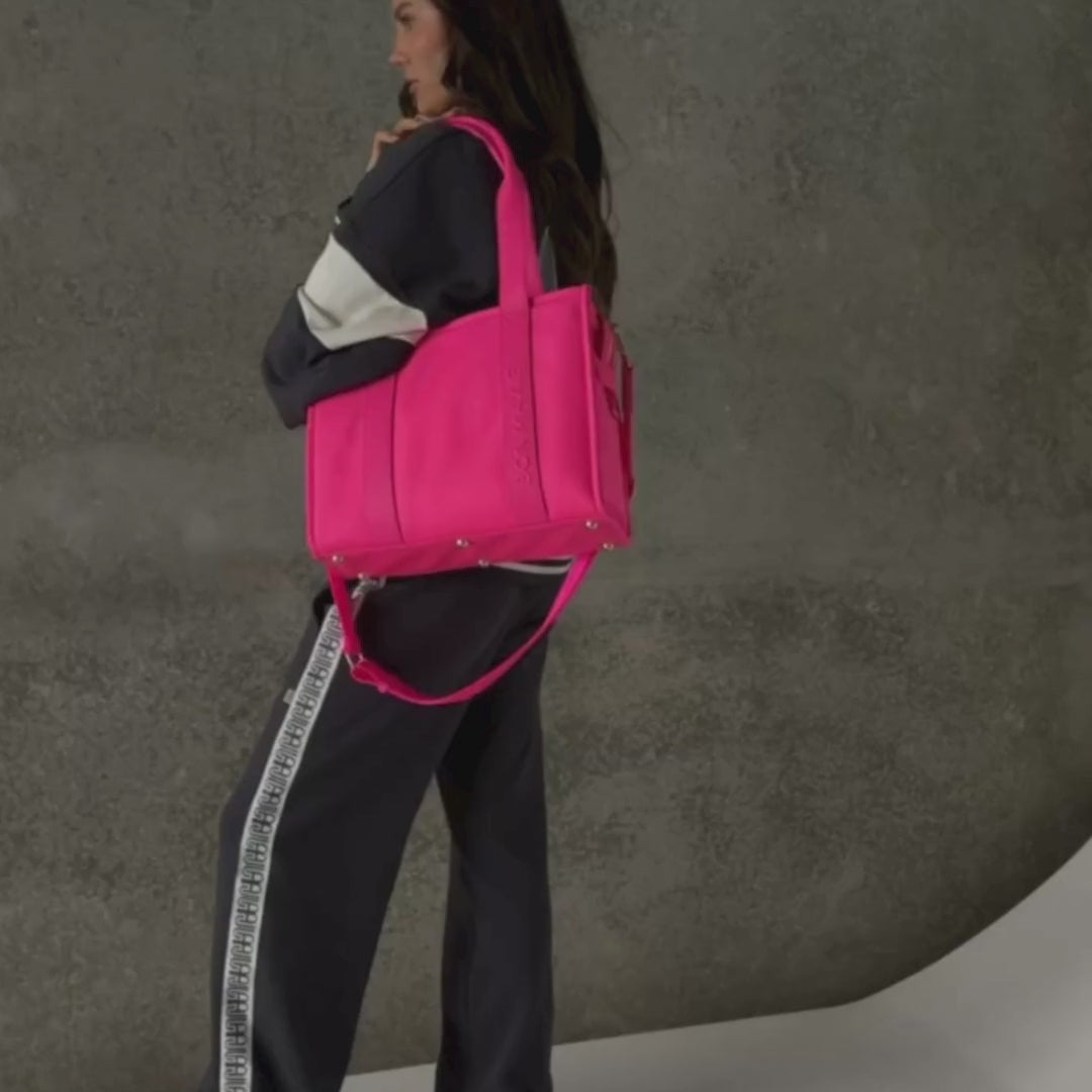Load video: Woman demonstrating medium nylon leather tote in neon pink