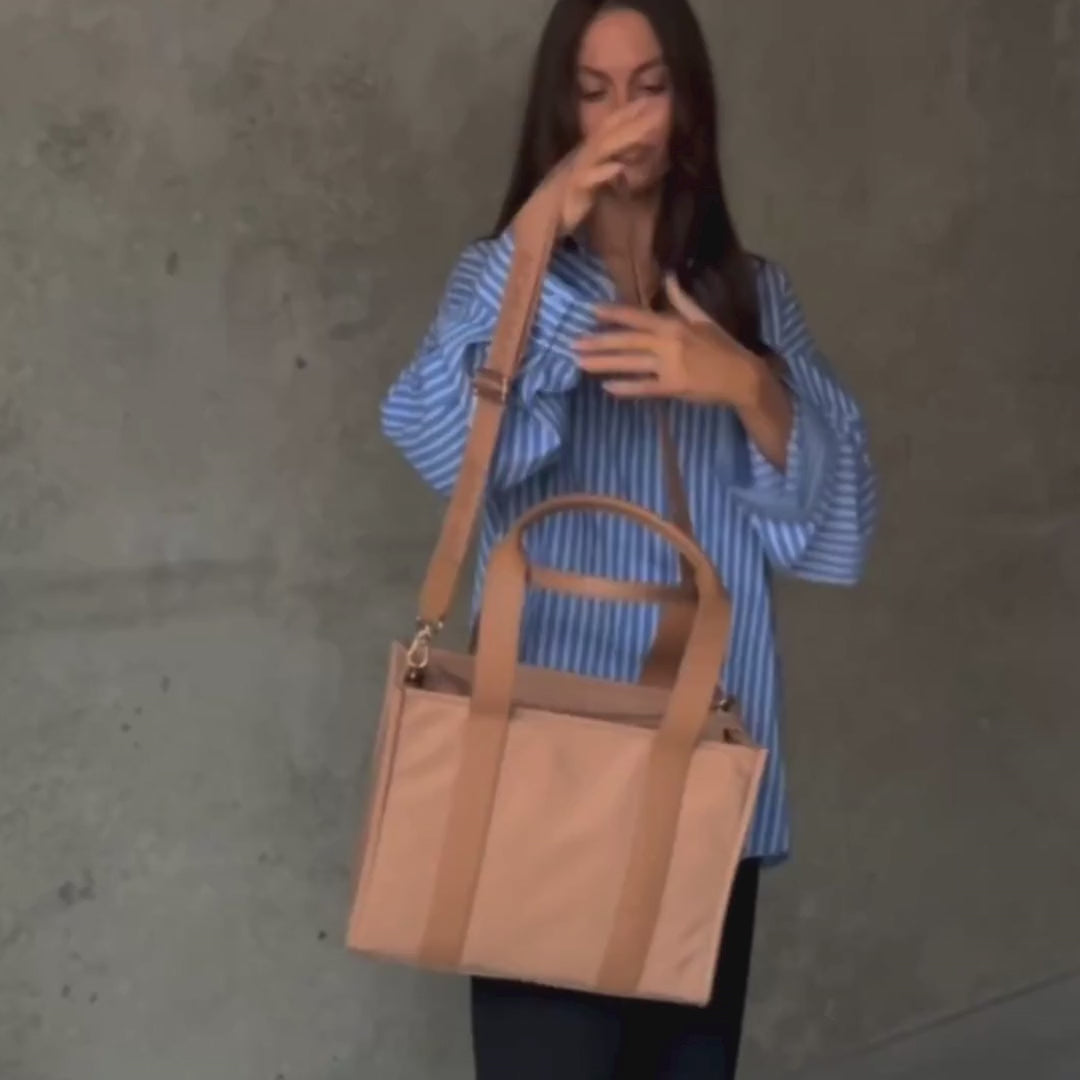 Load video: Woman demonstrating medium nylon leather tote in tan