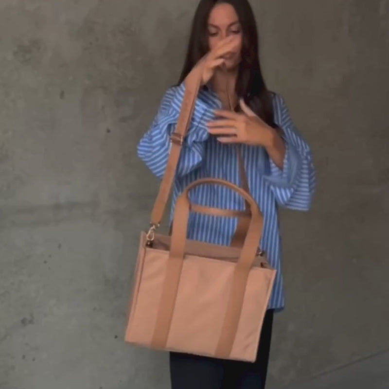 Woman demonstrating medium nylon leather tote in tan