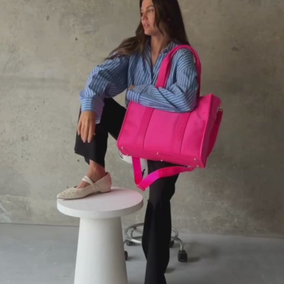 Load video: Woman demonstrating large nylon leather tote in neon pink