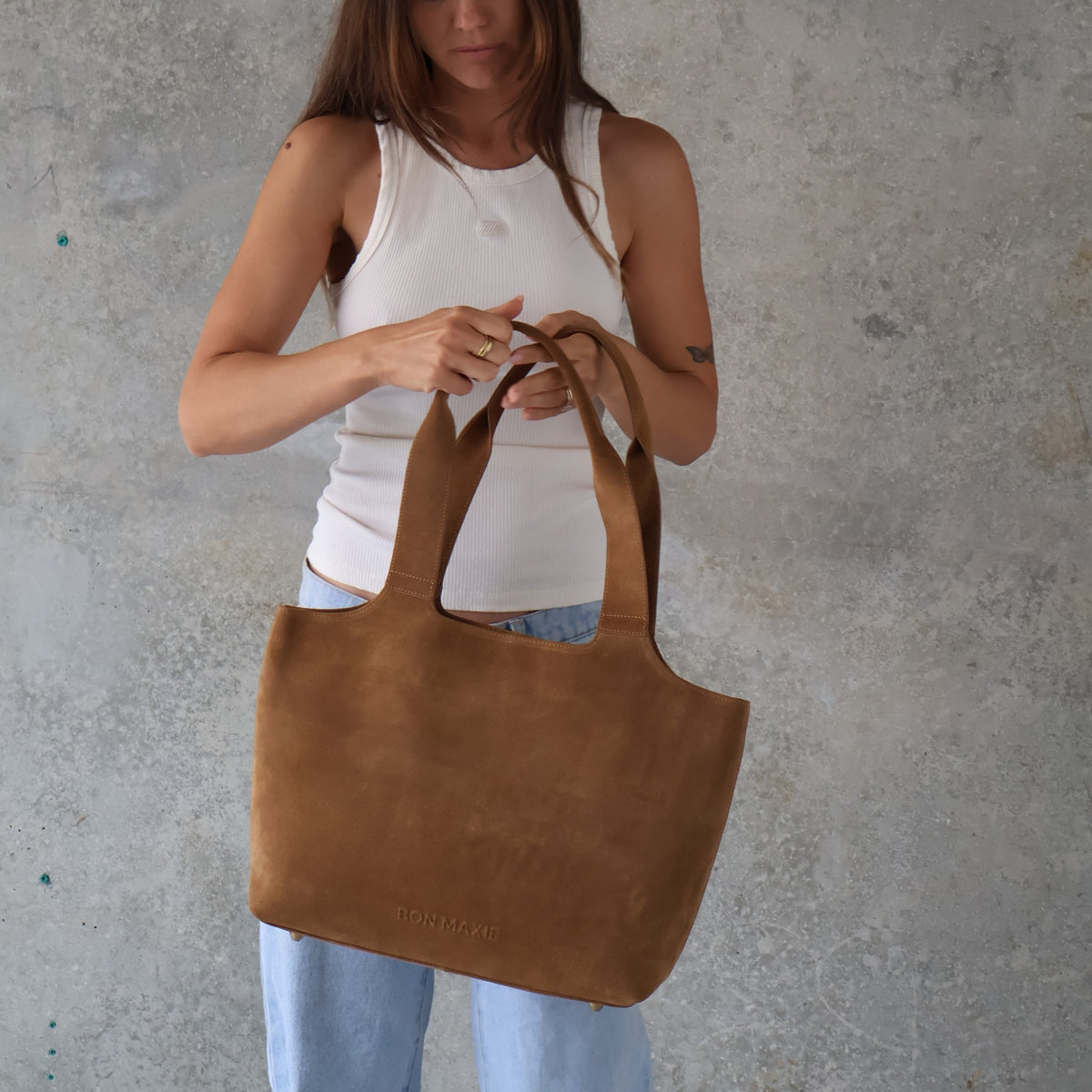 Maven Tote in Tan Suede, carried by the handles